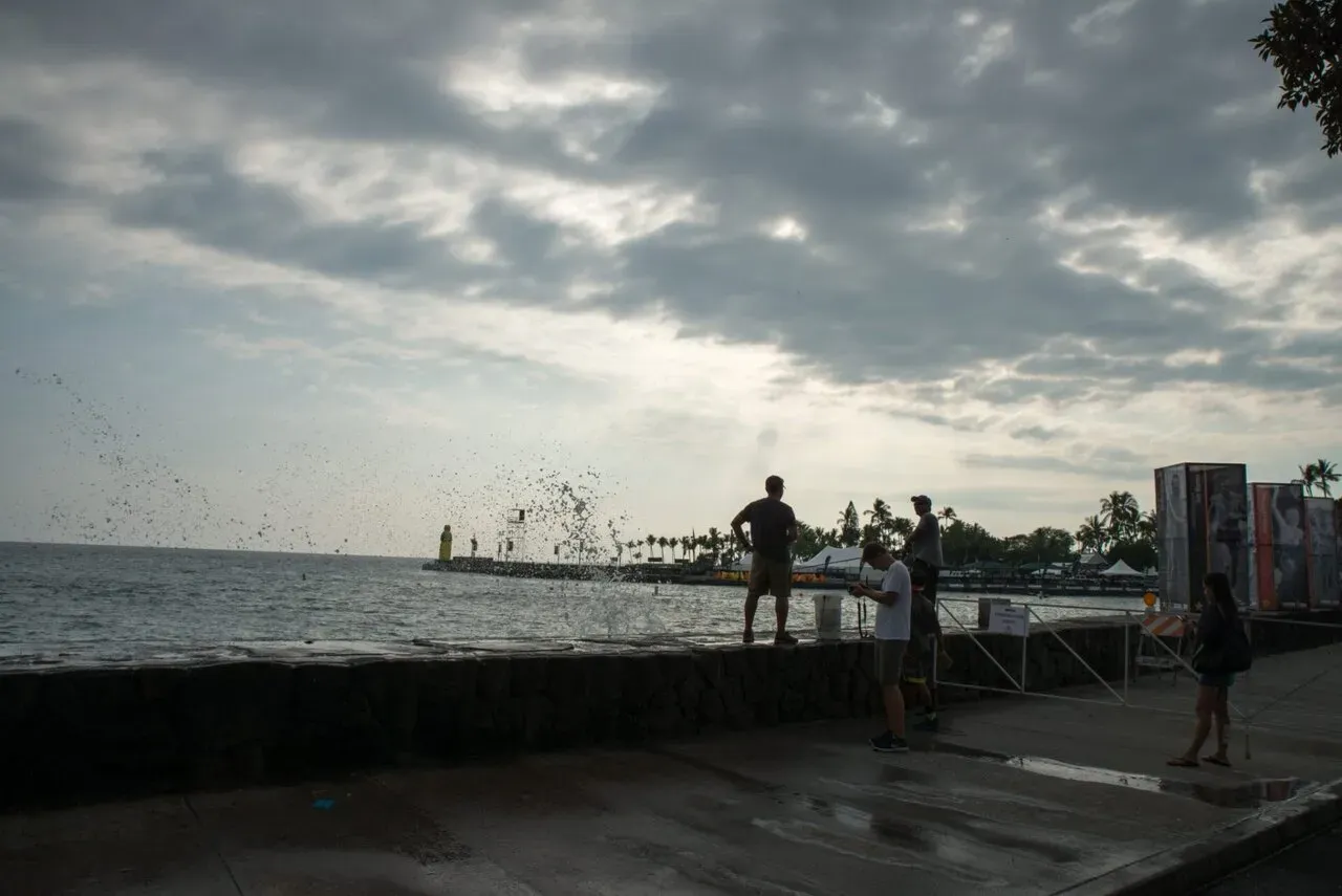 海岸で釣り人と波しぶきのシルエット